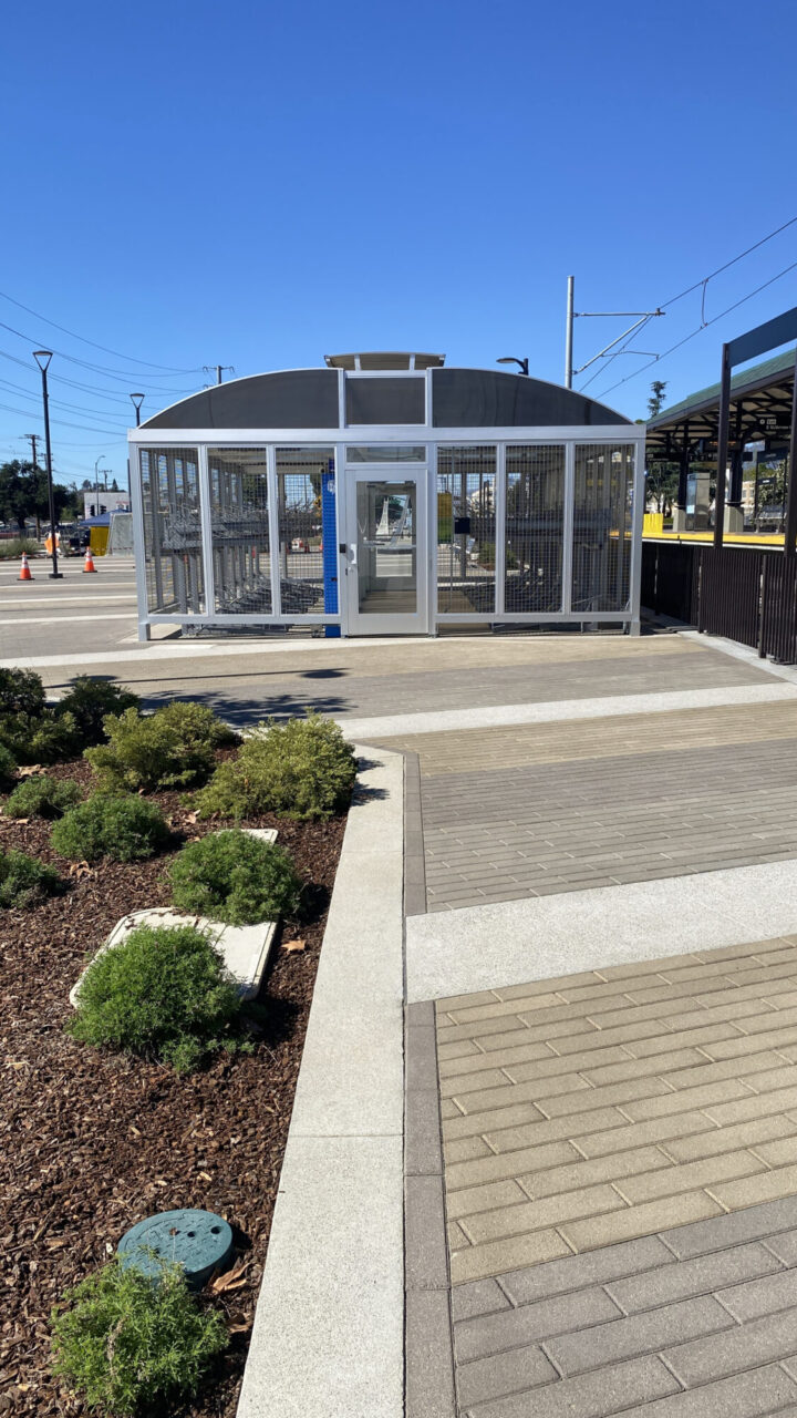 Bicycle storage unit at transit station with paver walkways in a modern outdoor setting.