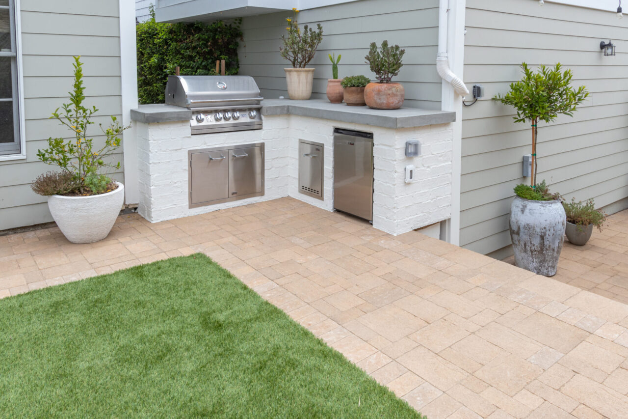 Aged edge paver walkway leading to built-in grill and mini fridge.