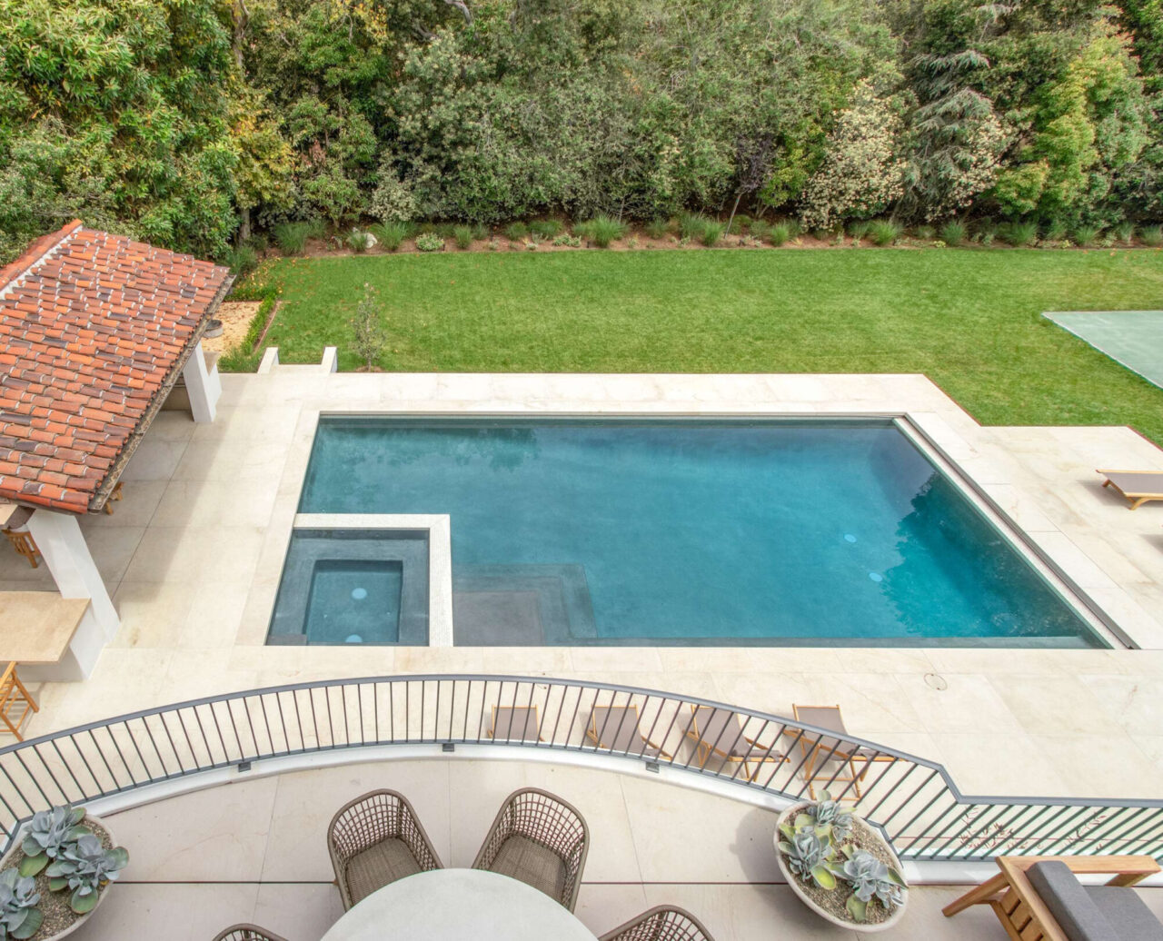 Natural stone paved balcony overlooking a pool and spa surrounded by natural stone decking.